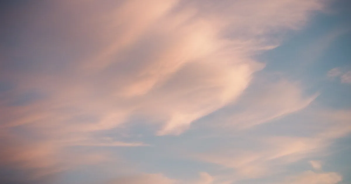 Soft pink and orange clouds in a golden hour sky, dreamy and ethereal
